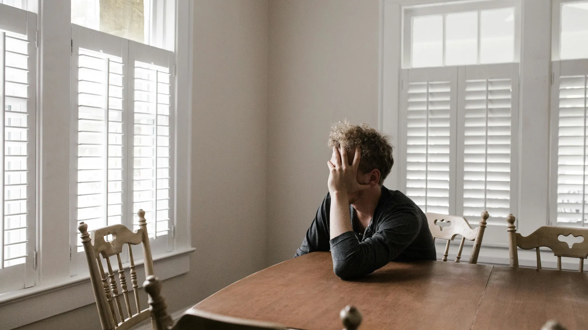 A man looks on from his table, lost in thought and filled with worry.