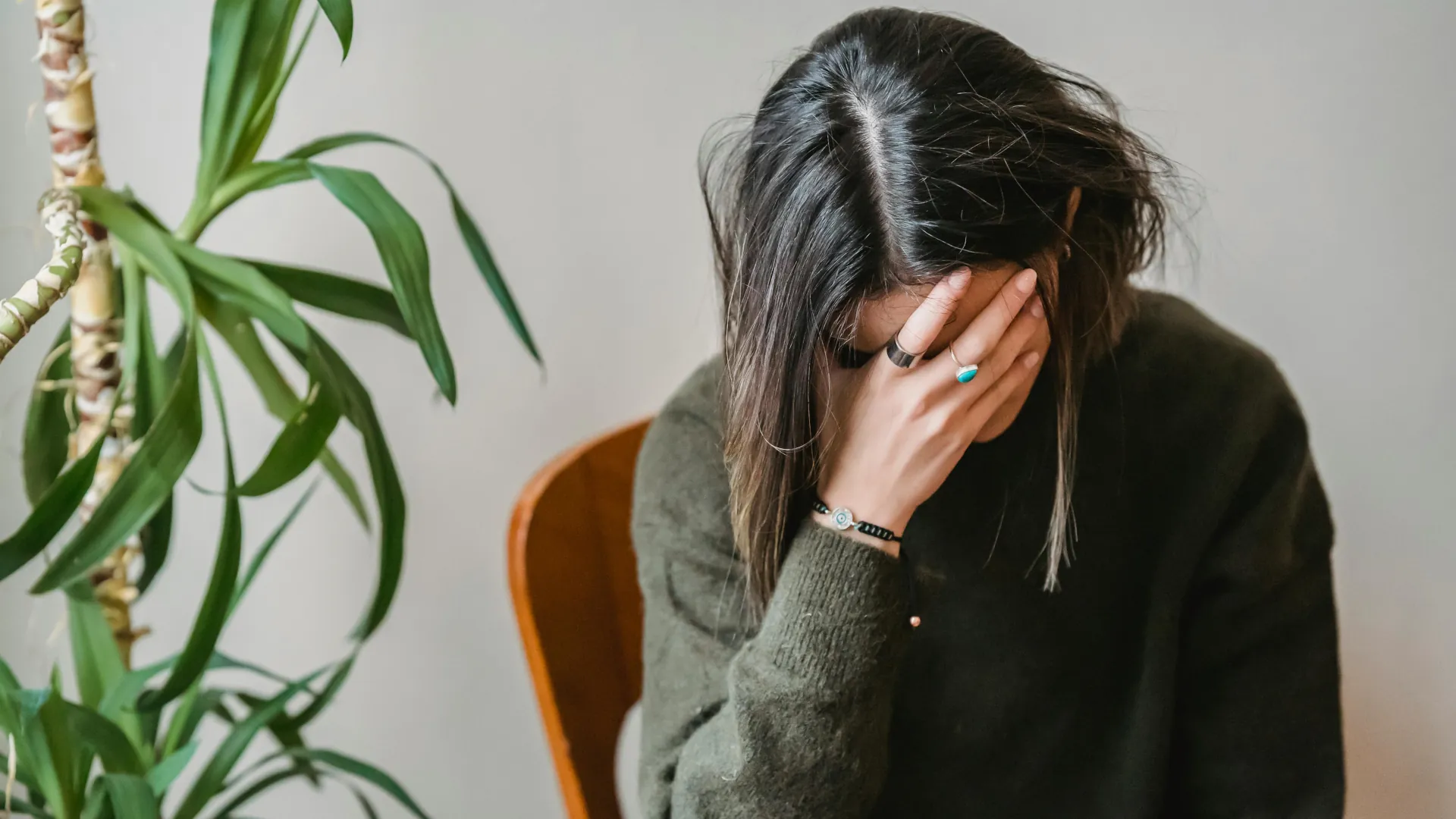 A young woman has her hand clasped over her face in a deep state of anxiety and worry.