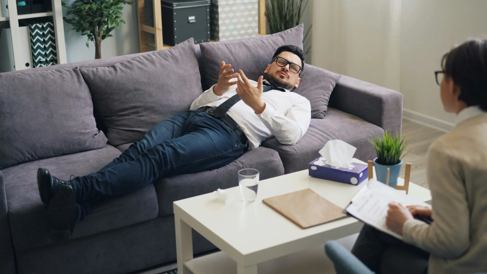 A young professional is taking part in Cognitive Behavioural Therapy with his therapist to get to the root of some personal issues.