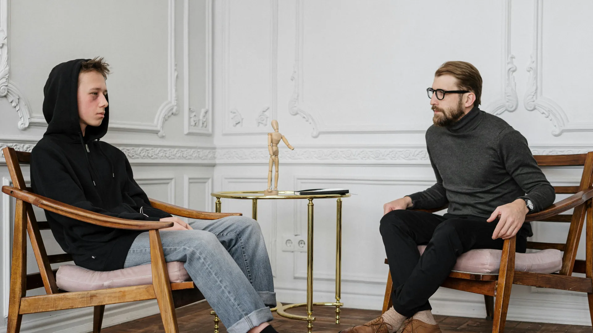 A young man who looks very upset and tired is seeking professional help from a counsellor.