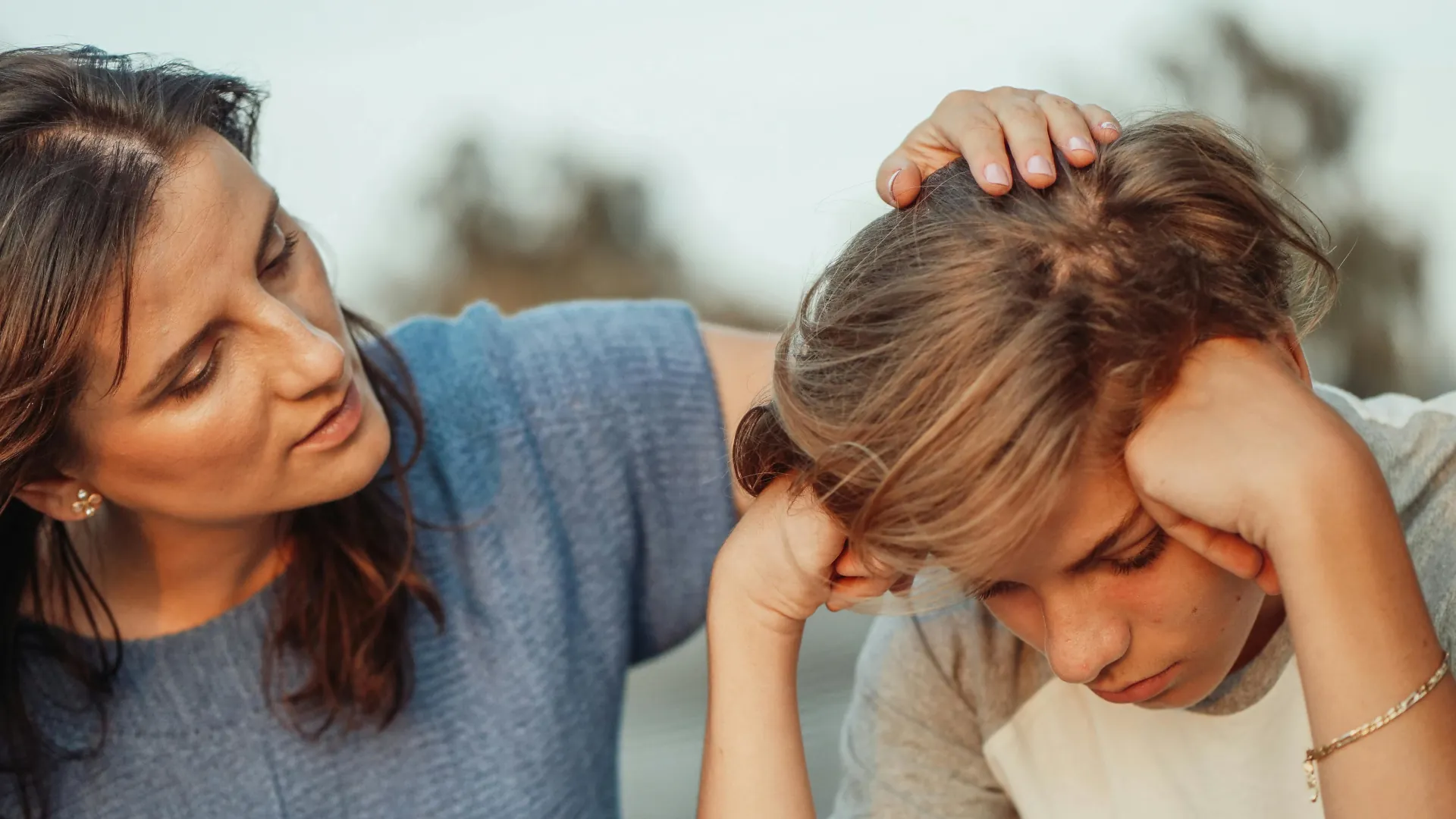 A young boy looks upset and unhappy, a child counsellor is talking with him about a sensitive subject.