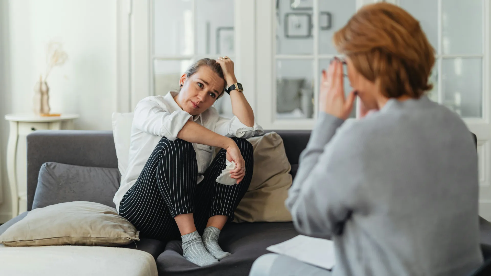 A woman is relaxing on a couch while having an open chat with her counsellor.