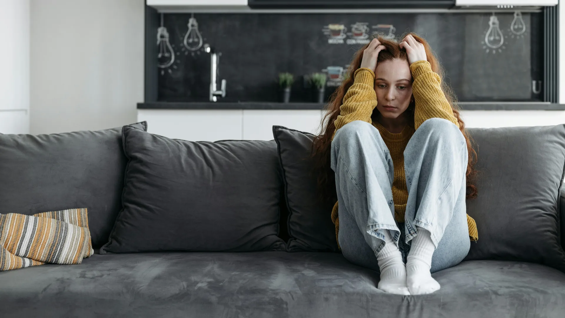 Young woman who is stressed, trying to relax on her couch.