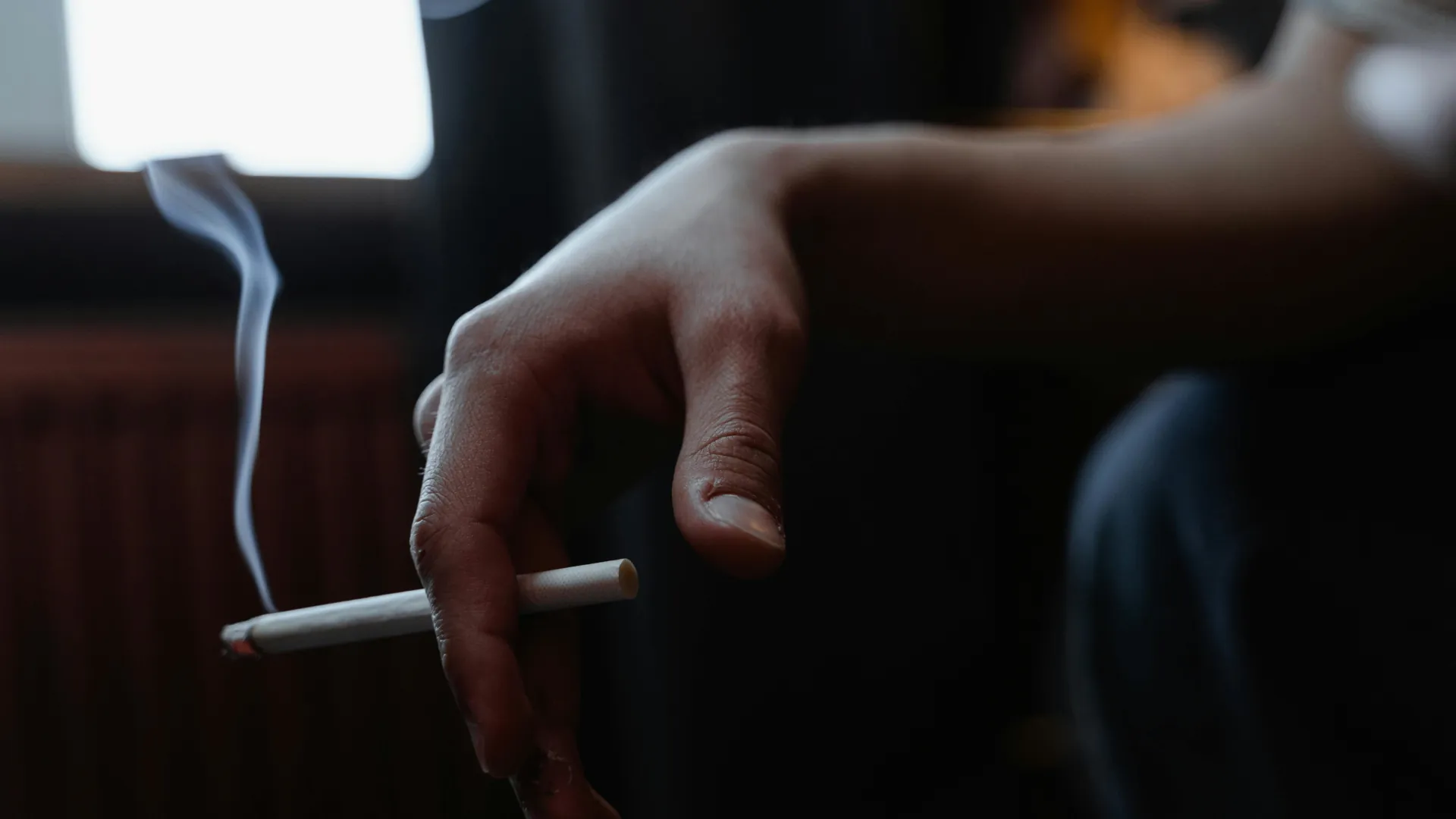 A young individual is sitting down smoking a cigarette.