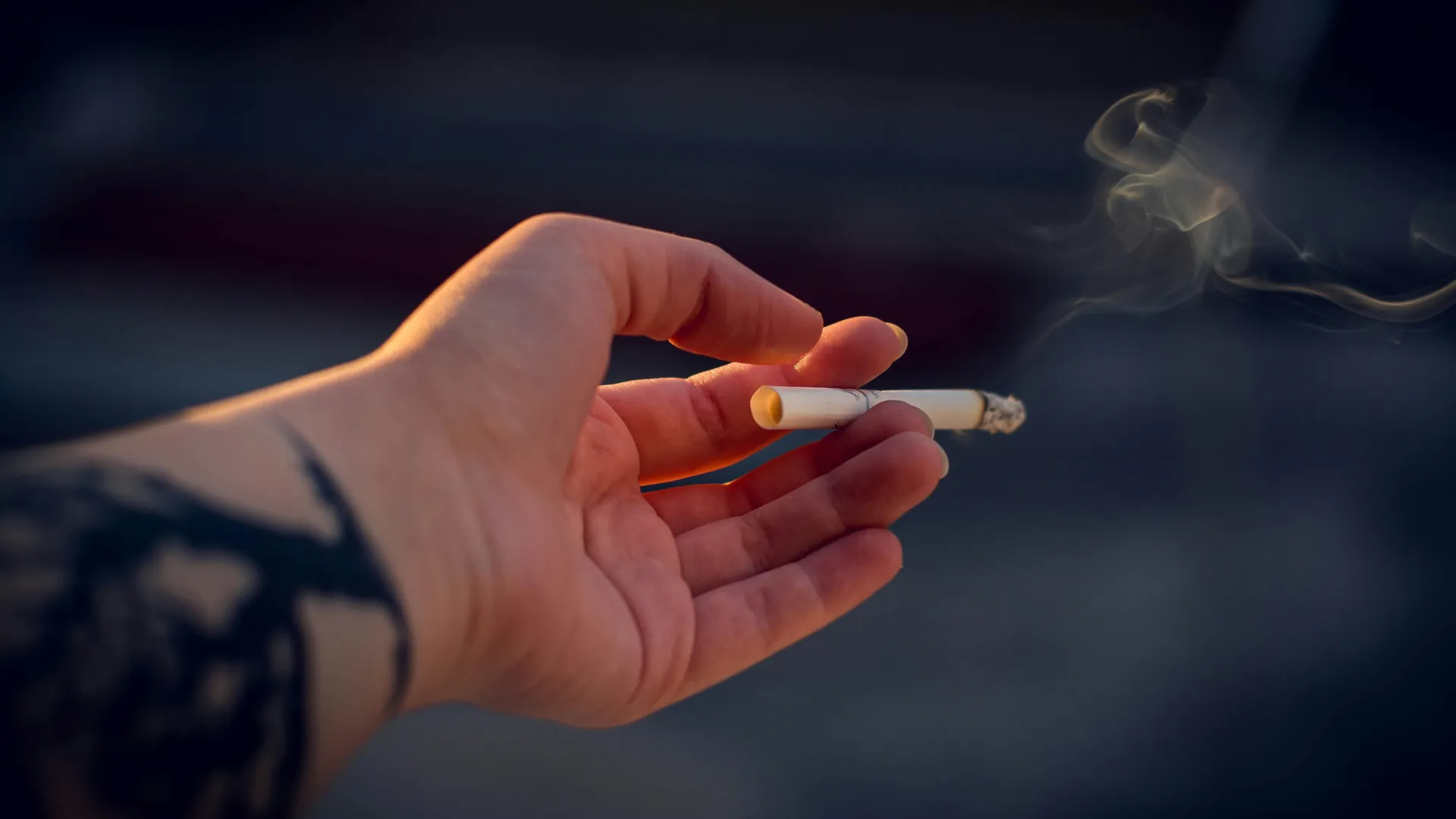 Young individual holding a lit cigarette.